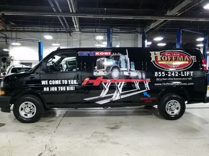 Black tow truck with Liftman branding parked inside a garage, side view.