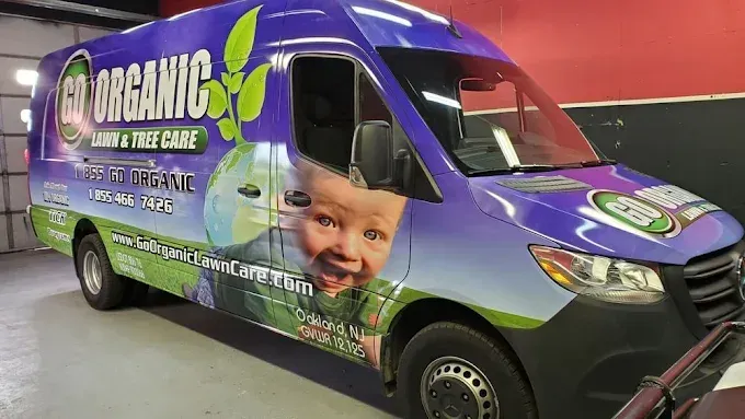 Purple and green Organic van with large produce branding parked indoors