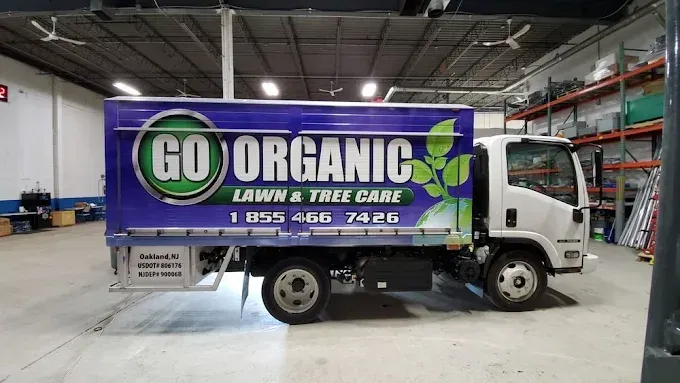 White work truck with green “GO ORGANIC Lawn & Tree Care” logo parked in a warehouse