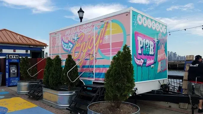 Pastel pink and turquoise food truck with colorful “Dough” branding at an outdoor market.