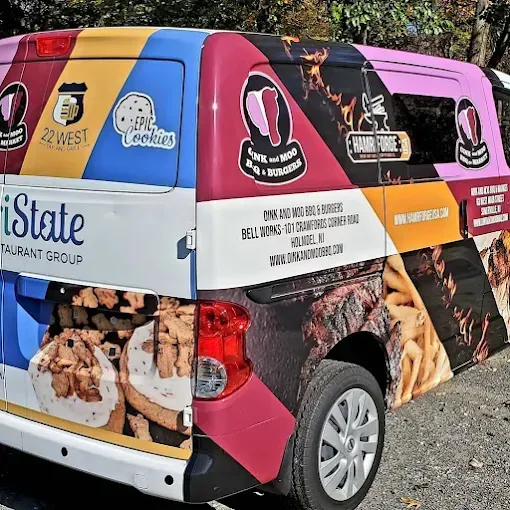 Colorful branded delivery van with food photos parked outdoors on gravel