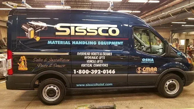 Sissco material handling equipment van parked indoors, black wrap with large white and yellow logo.