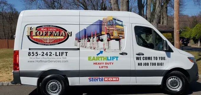 White service van with Hoffman and EarthLIFT branding parked outdoors with trees in the background