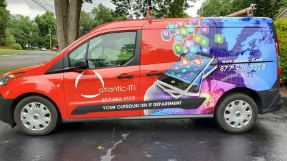 Red and purple branded service van parked on a wet street beside a tree, with a smartphone graphic on the side.