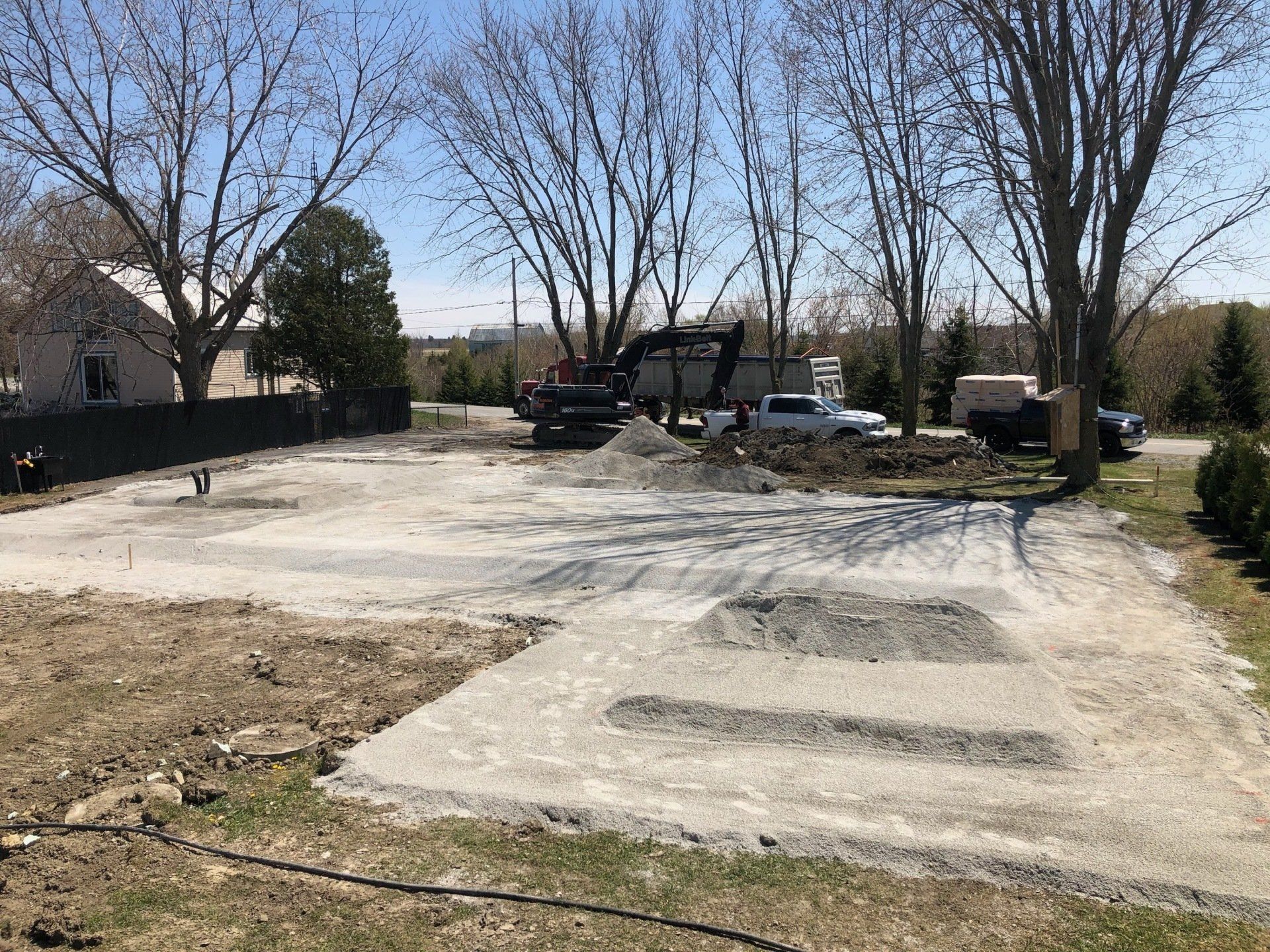 Un chantier de construction avec beaucoup de terre et des arbres en arrière-plan.