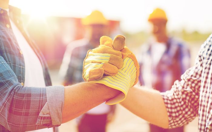 Un groupe d'ouvriers du bâtiment se serrent la main sur un chantier de construction.