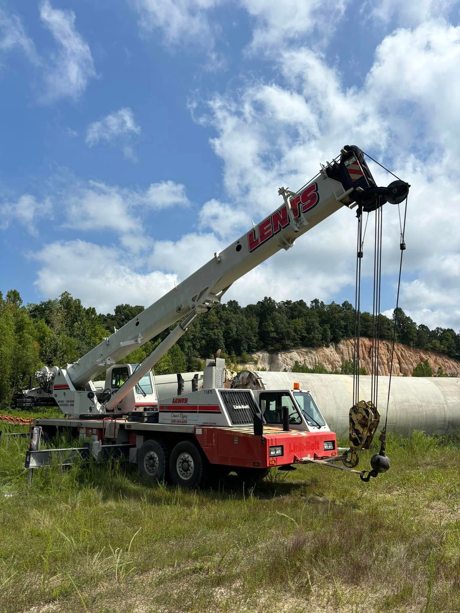 A large crane is sitting in the middle of a grassy field.