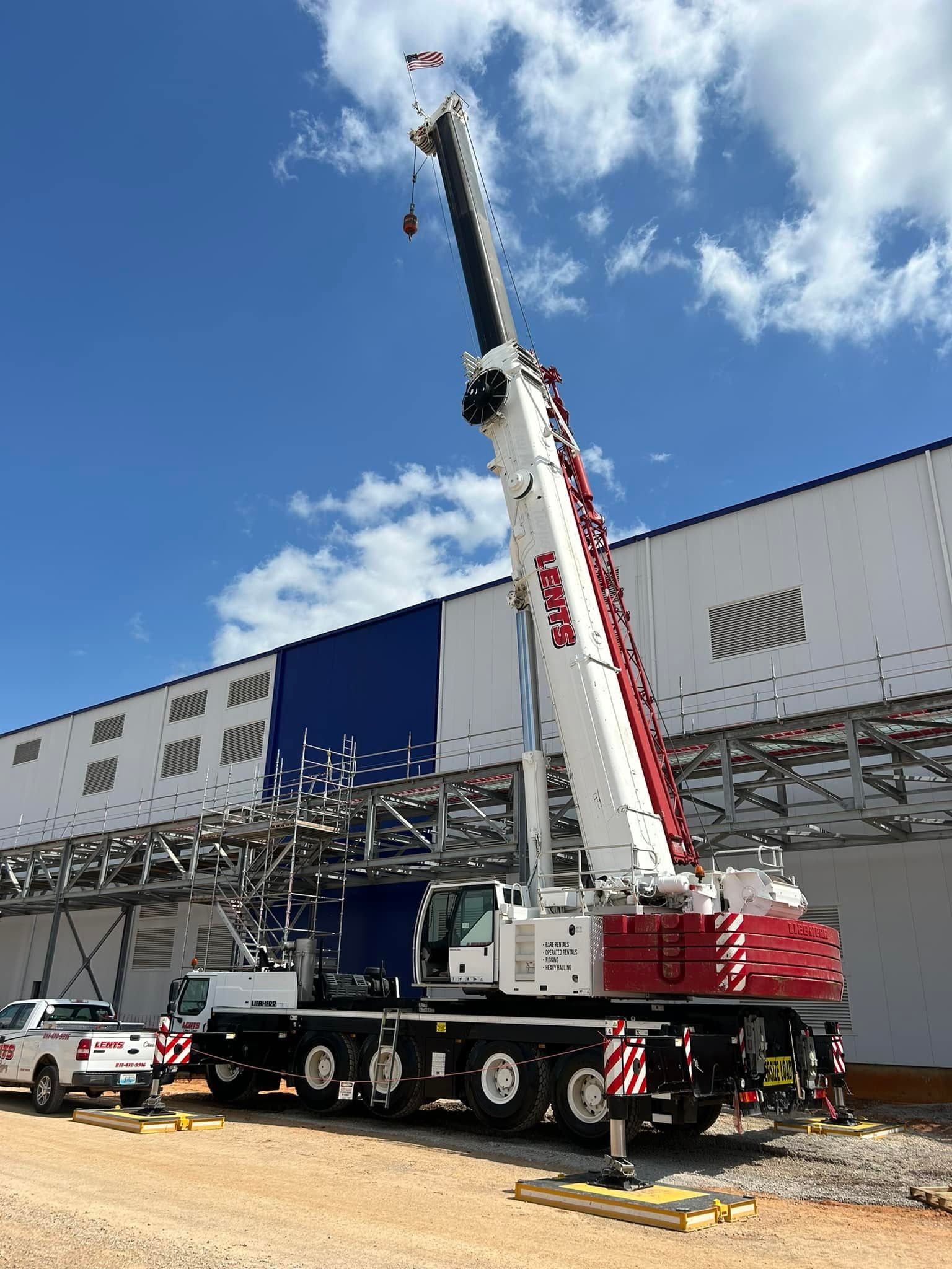 A large crane is parked in front of a large building.