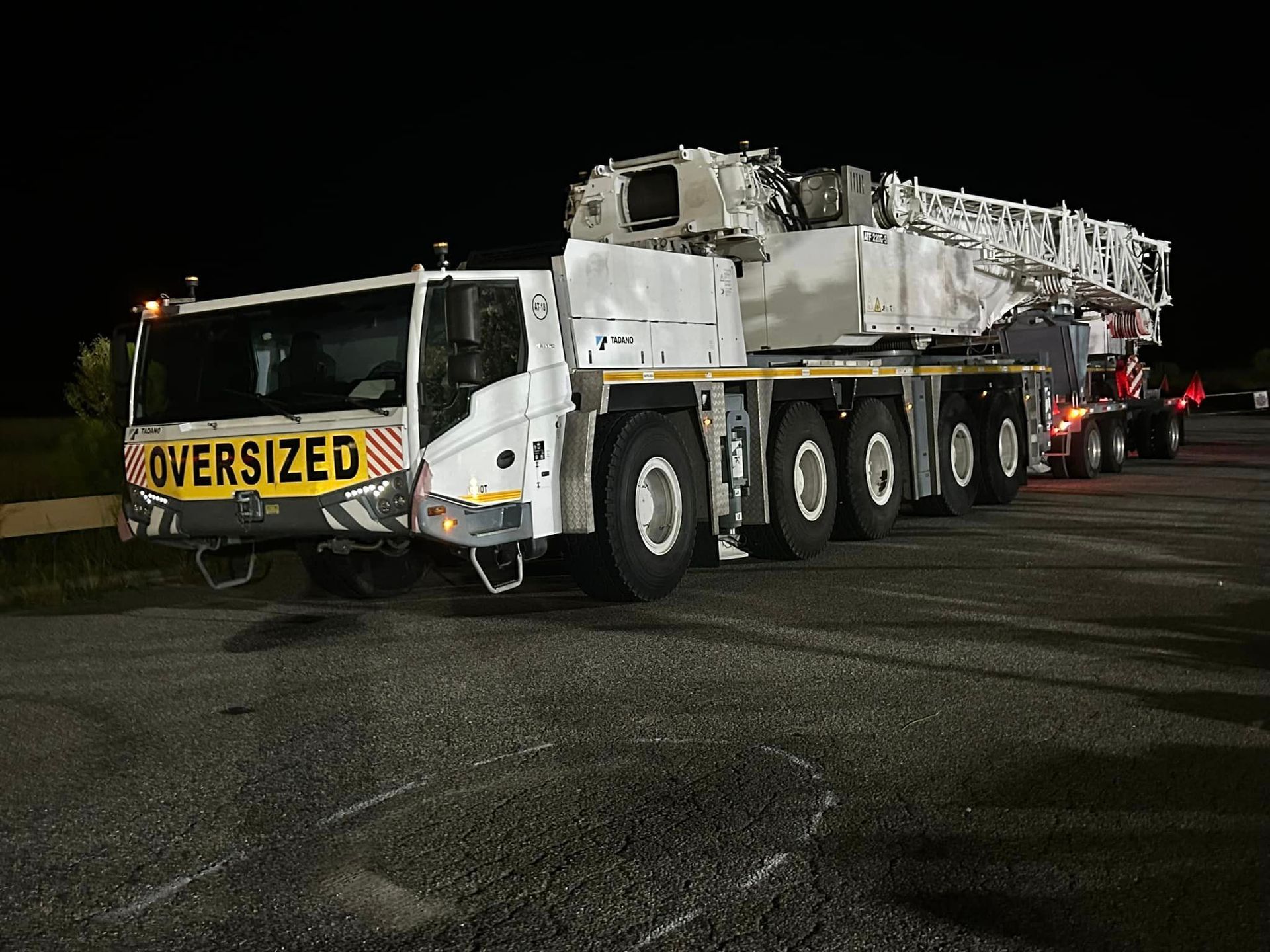 An oversized truck is parked in a parking lot at night.