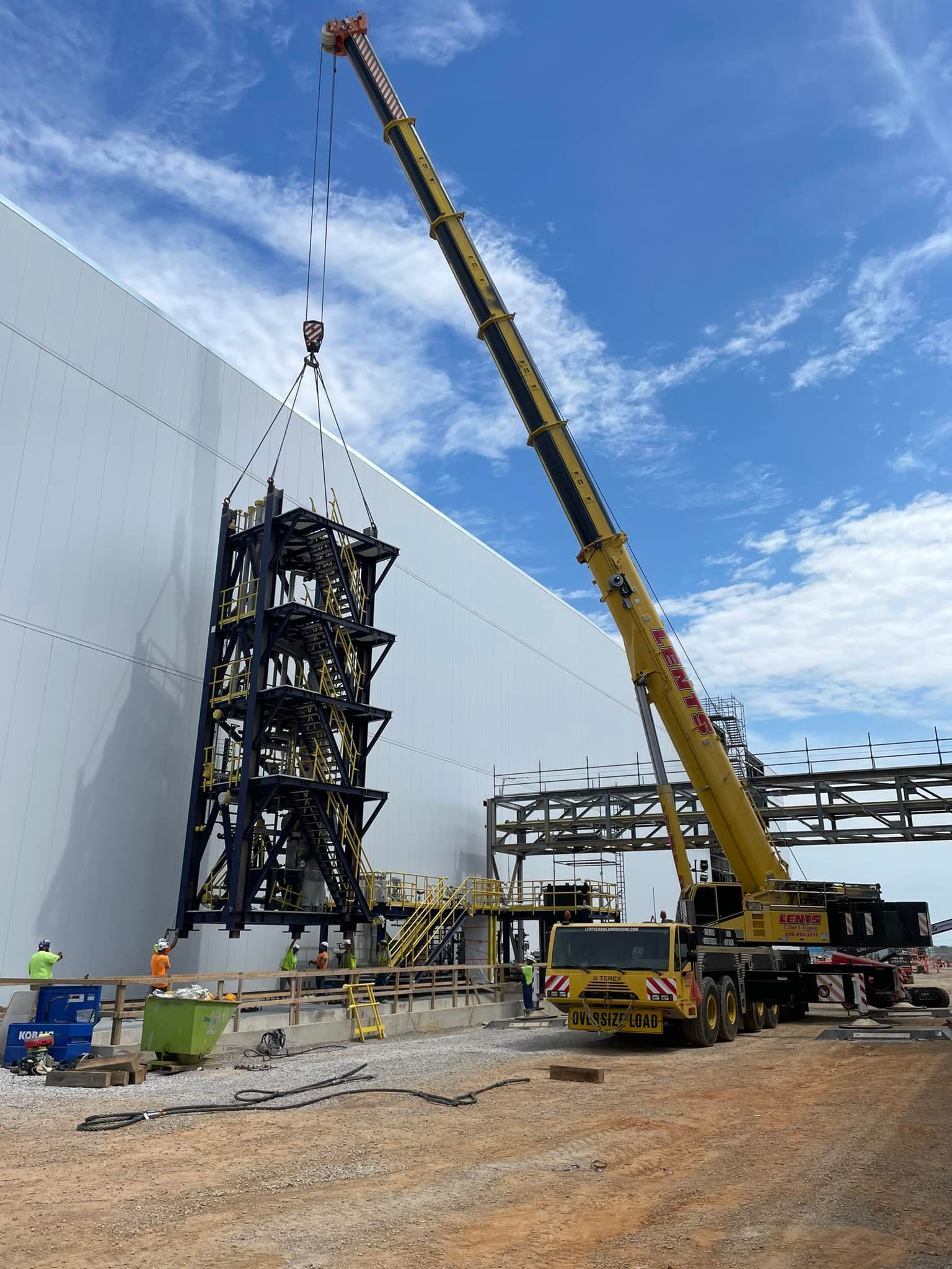 A large crane is lifting a tower on a construction site.