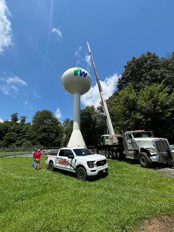 Two trucks are parked in front of a water tower.