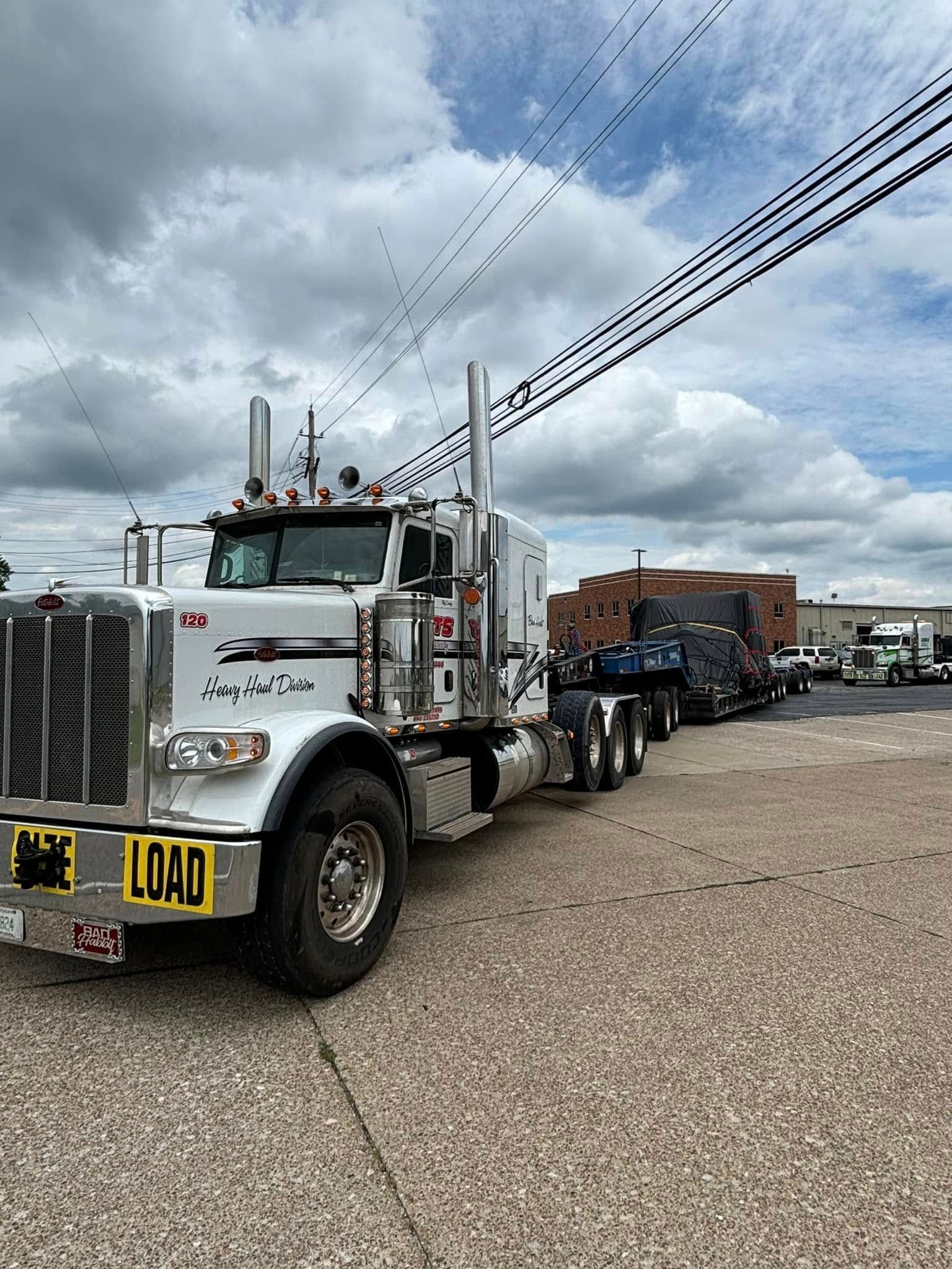 A semi truck is parked on the side of the road in a parking lot.
