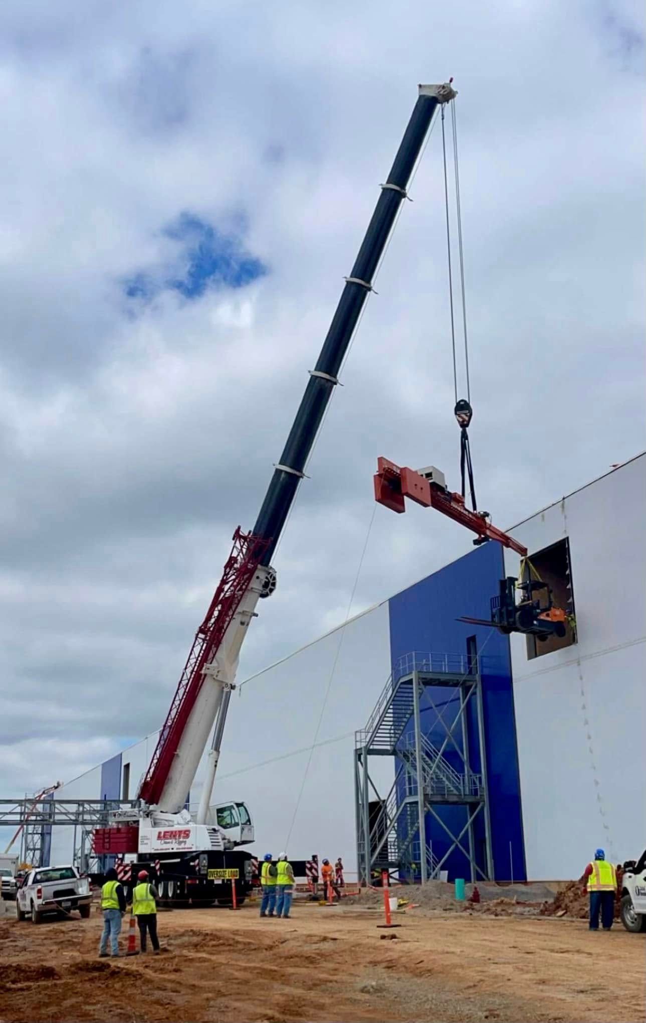 A large crane is lifting a bucket on top of a building.