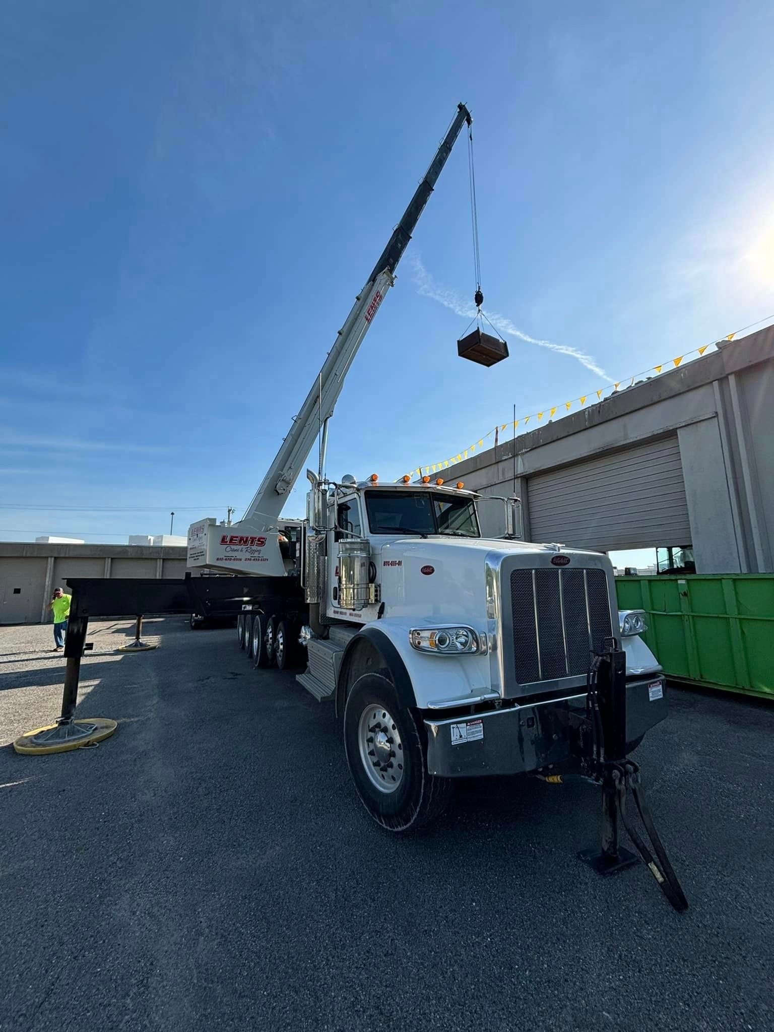A semi truck with a crane attached to it is parked in a parking lot.
