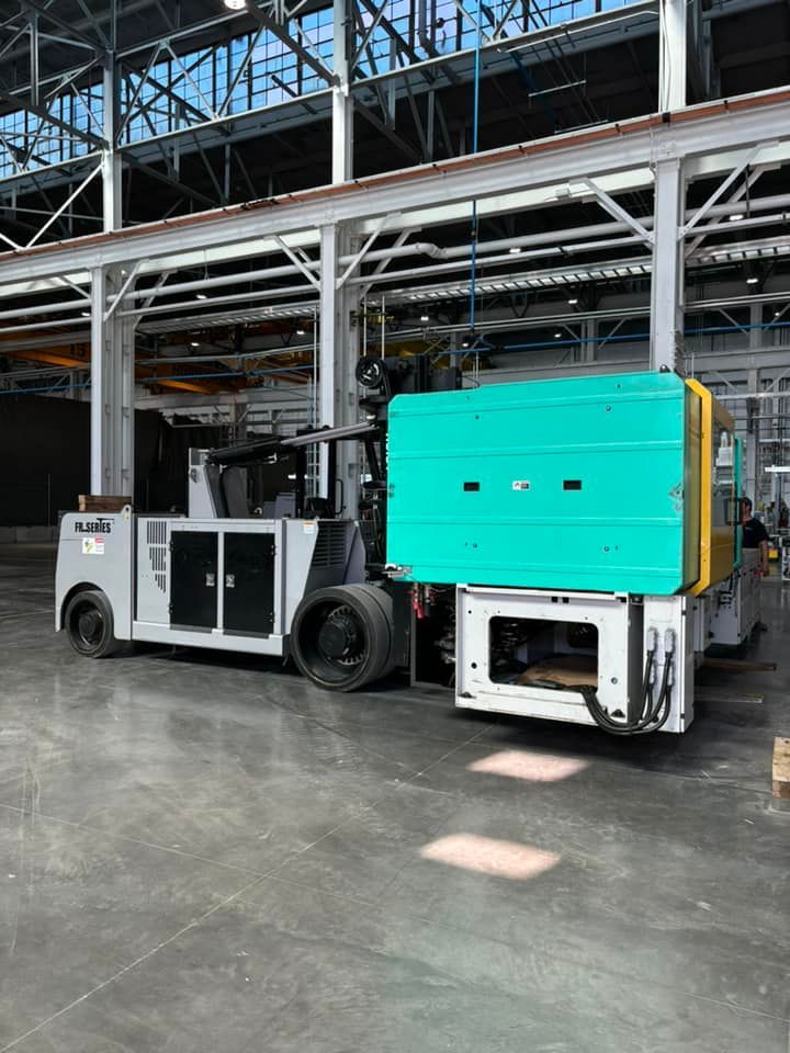 A forklift is loading a machine into a warehouse.