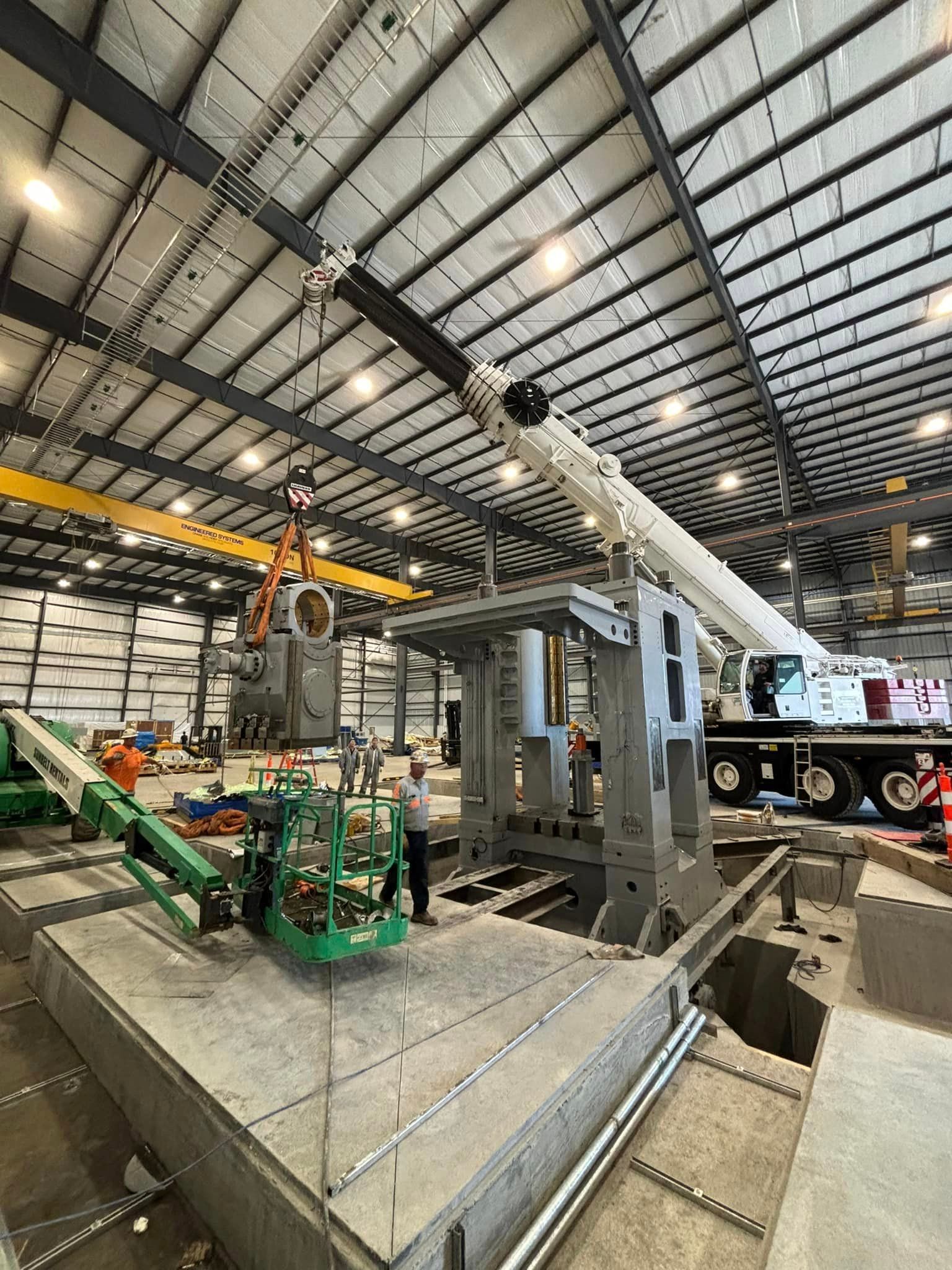 A large crane is being used to lift a machine in a large building.