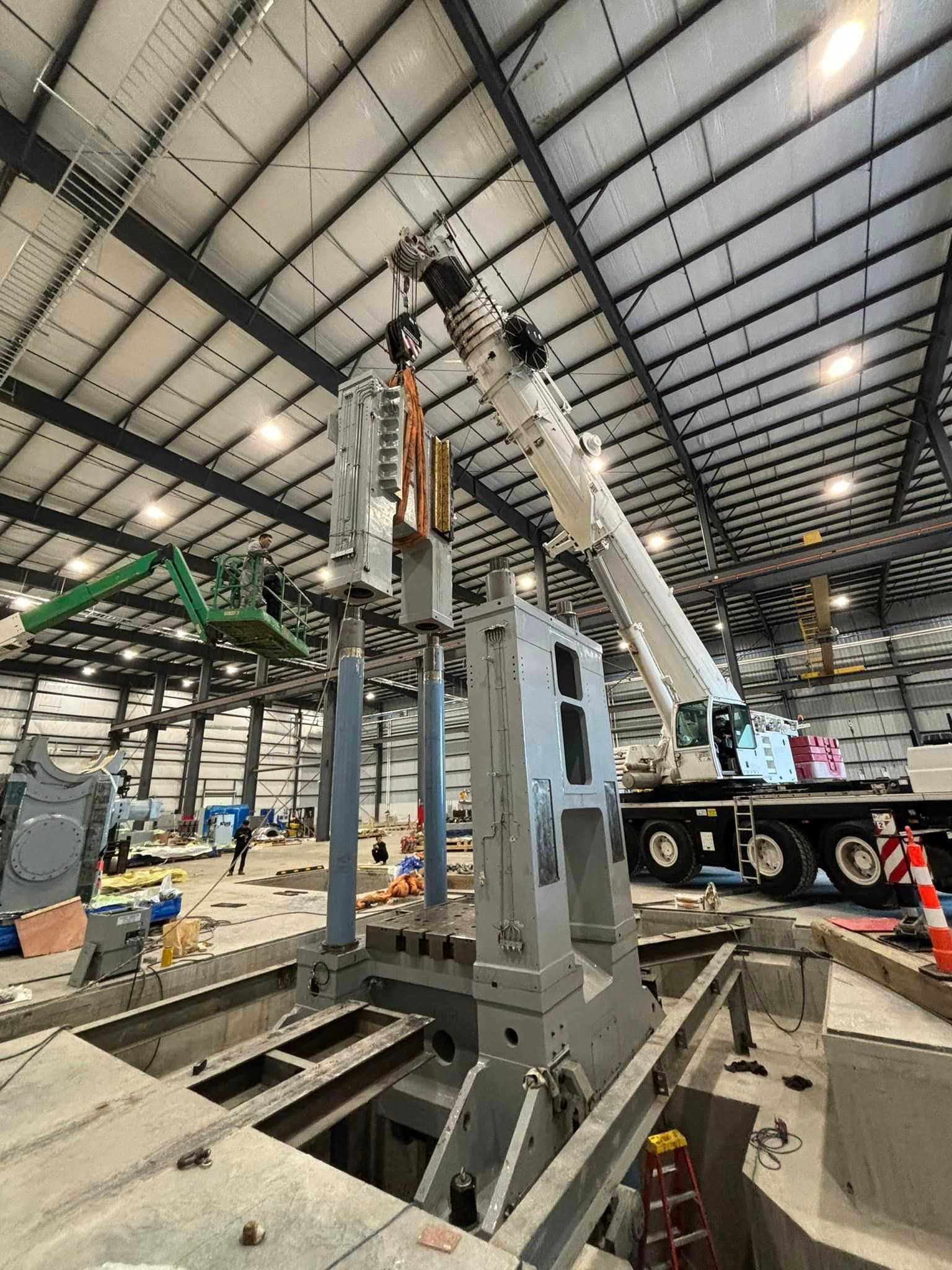 A crane is lifting a large piece of metal in a large warehouse.