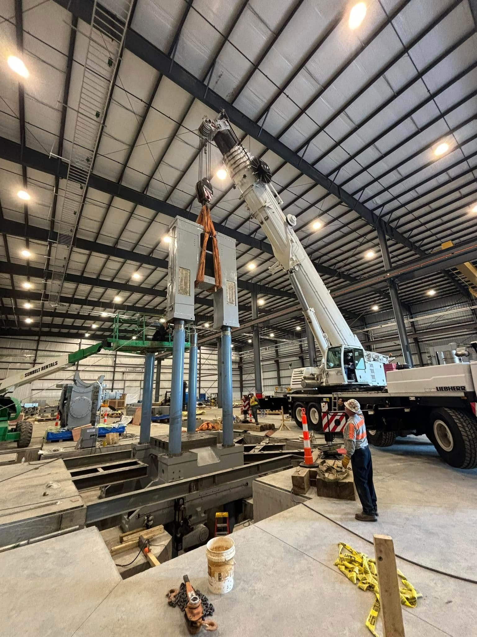 A large crane is being used to lift a large piece of metal in a warehouse.