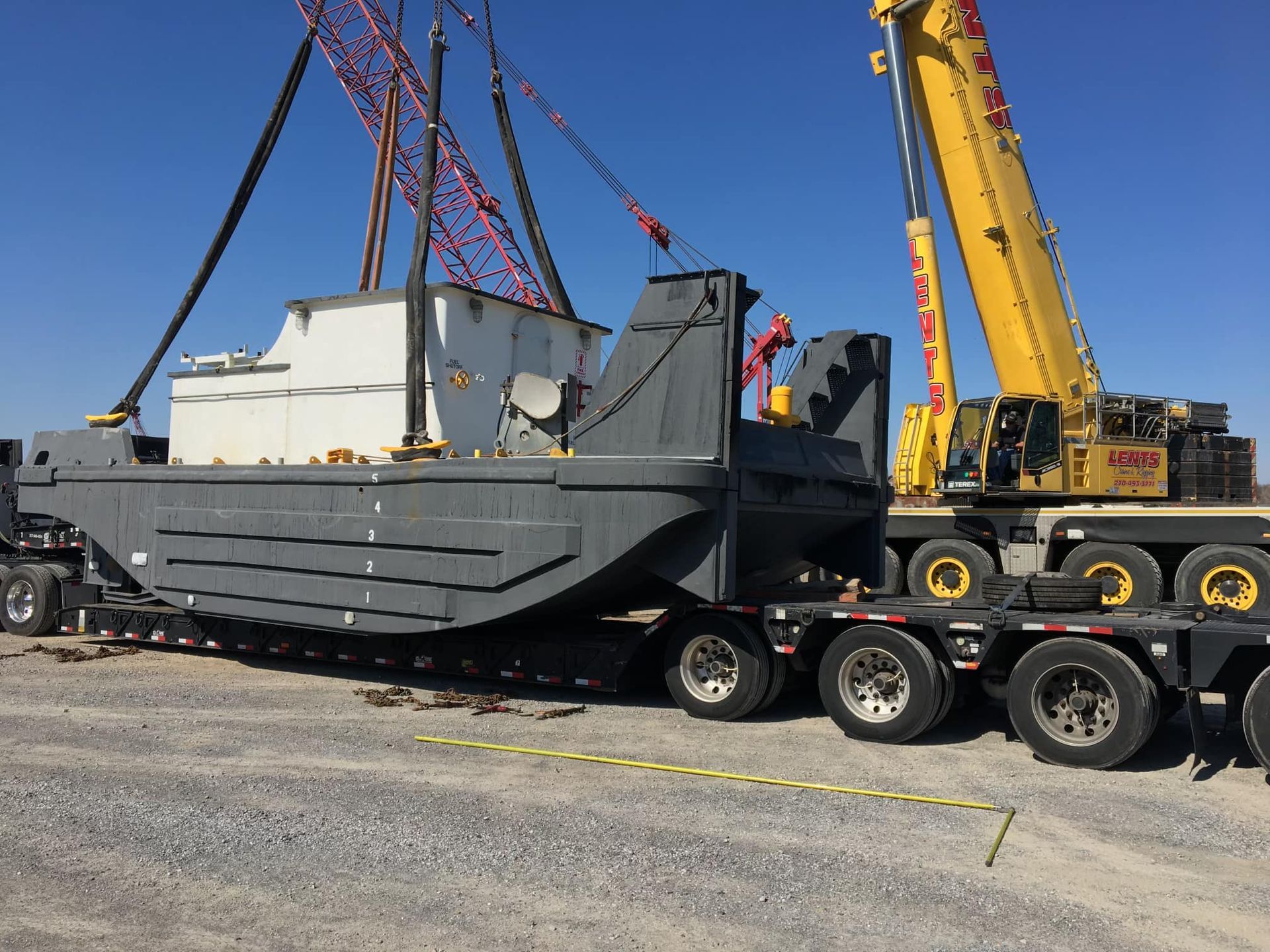 A large boat is being lifted by a crane on a trailer