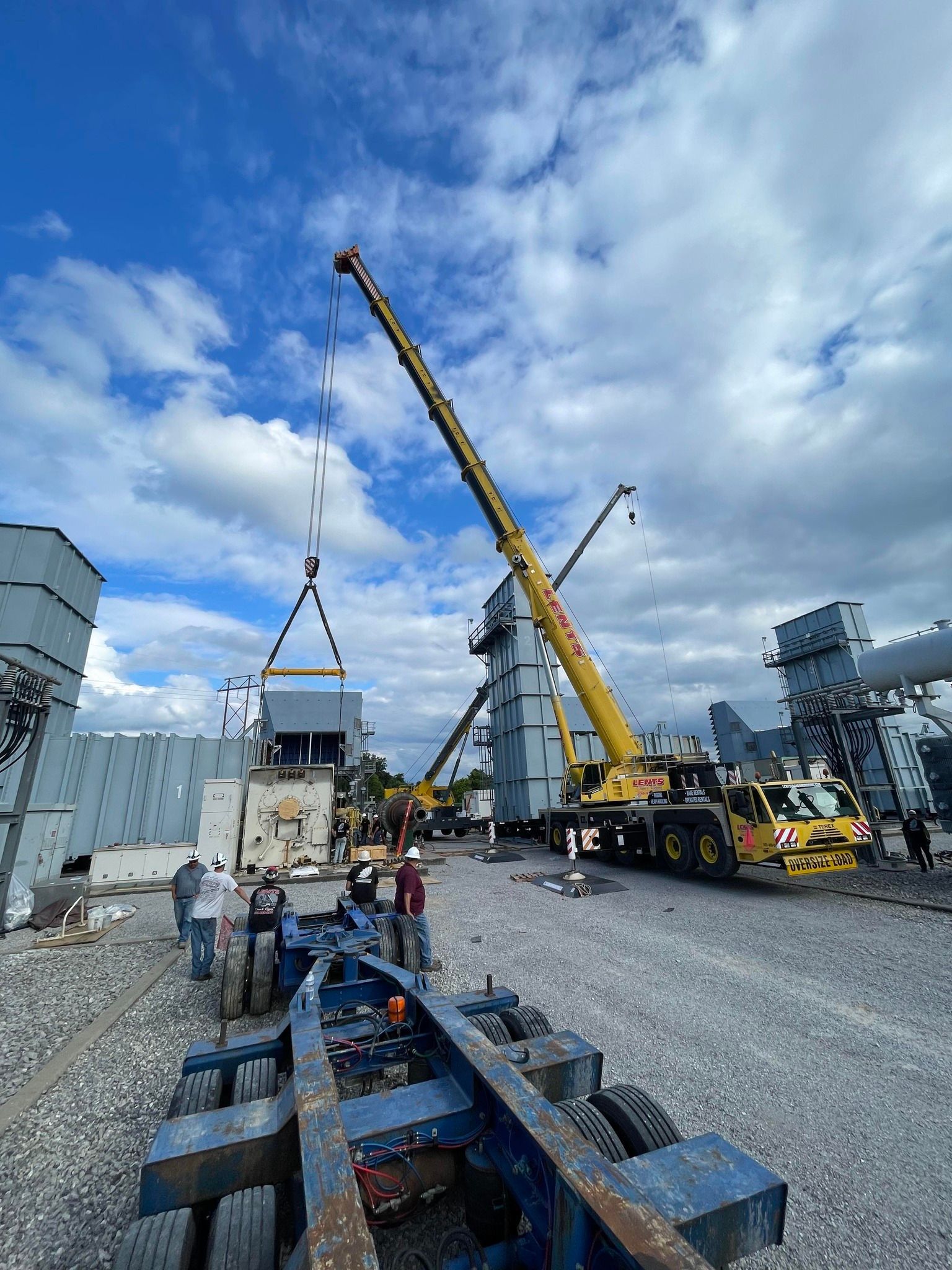 A large yellow crane is lifting a building in a construction site.