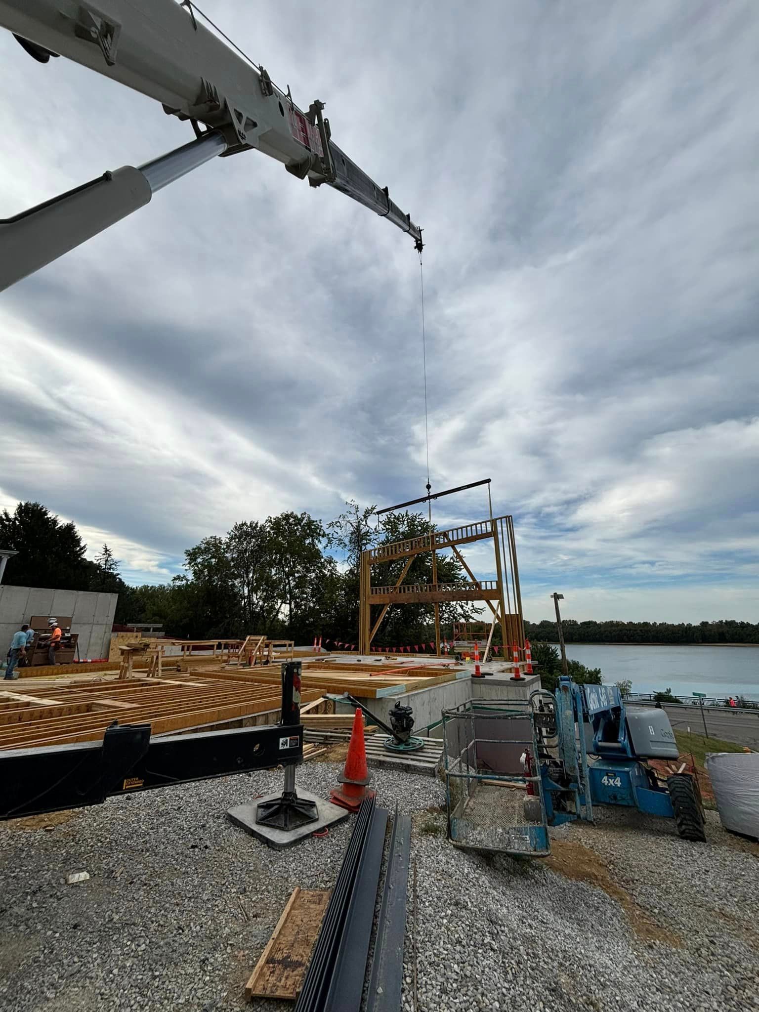 A large crane is lifting a wooden structure on a construction site.