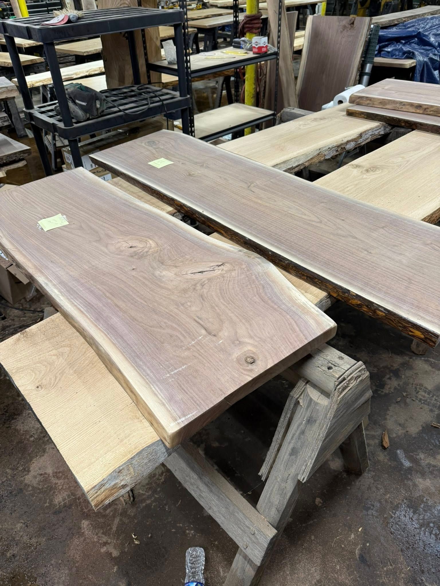Two weathered wooden planks resting on sawhorses in a workshop or lumber yard
