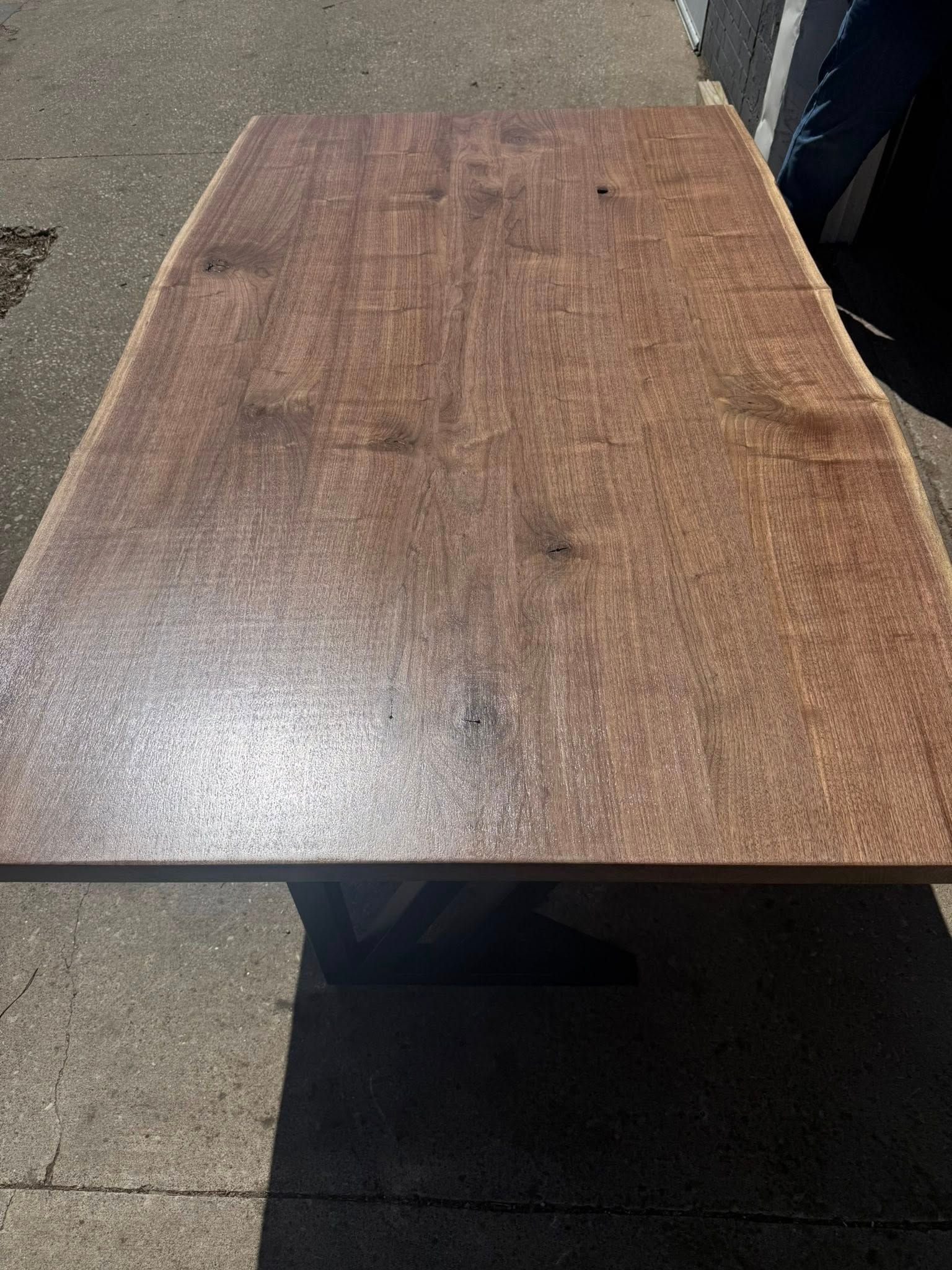 Wooden desk surface with a dark metal frame on a carpeted floor