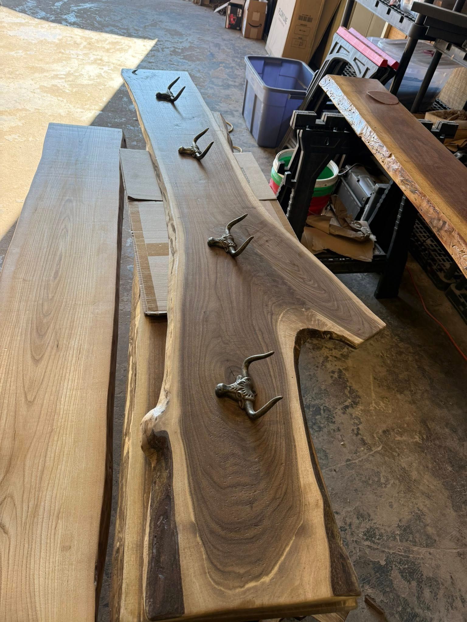 Several unfinished wooden boards with clamps in a workshop, showing wood grain and a workbench.