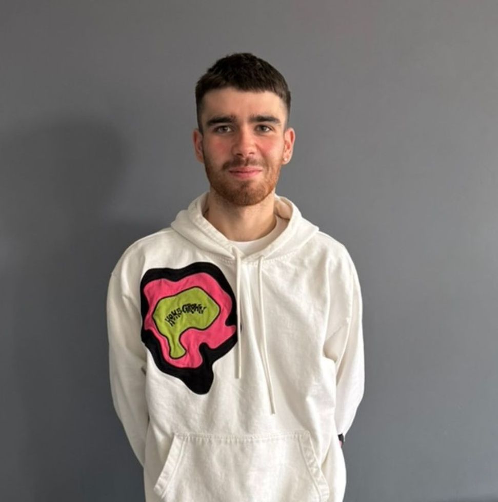A man with a beard is wearing a white hoodie with a colorful design on it.