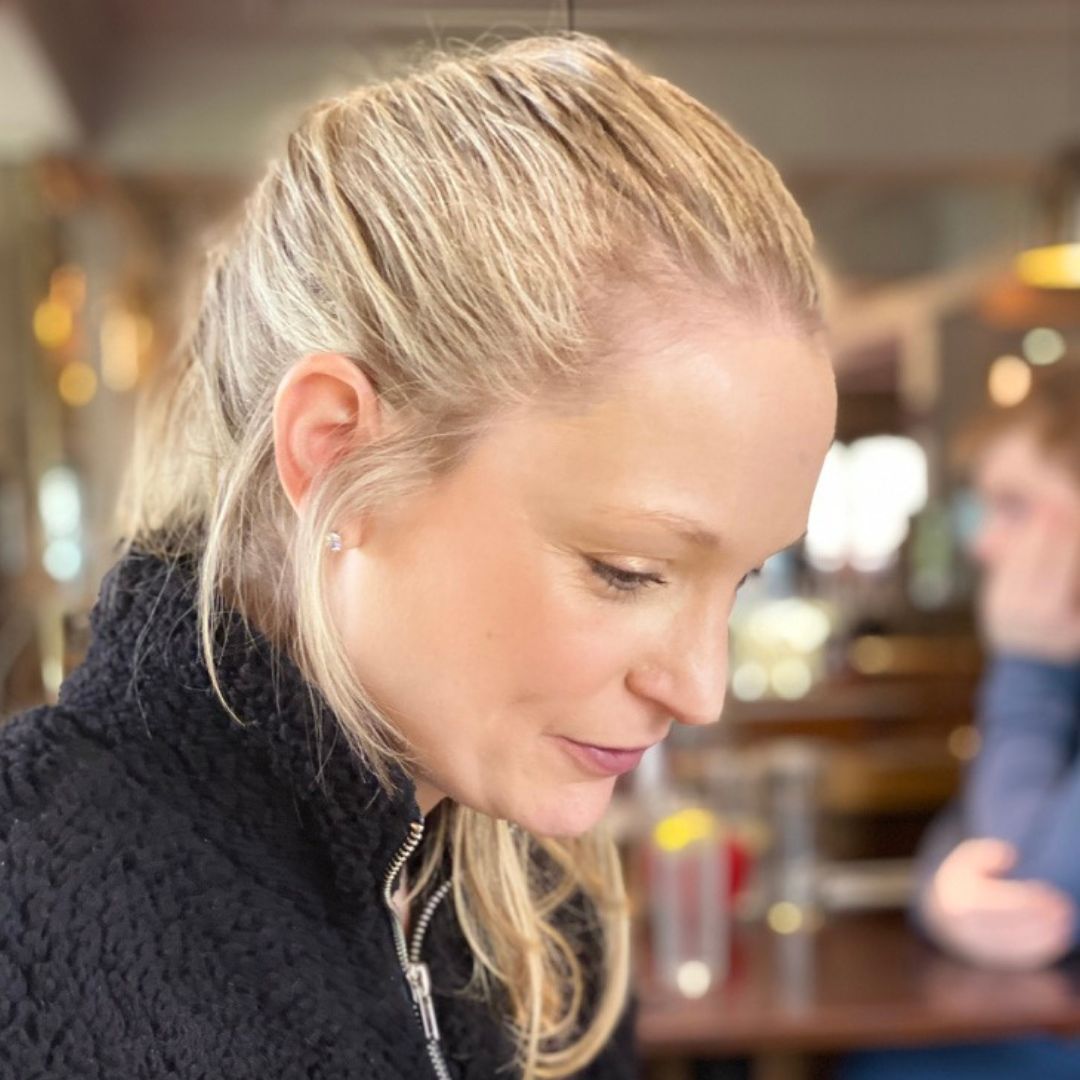 A woman with blonde hair is wearing a black sweater