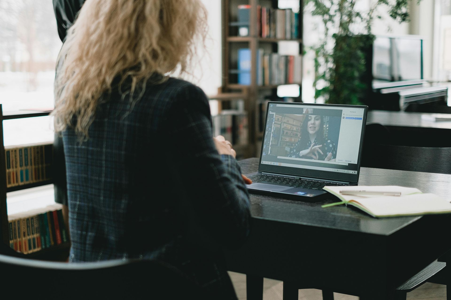 A woman is sitting at a desk using a laptop computer.