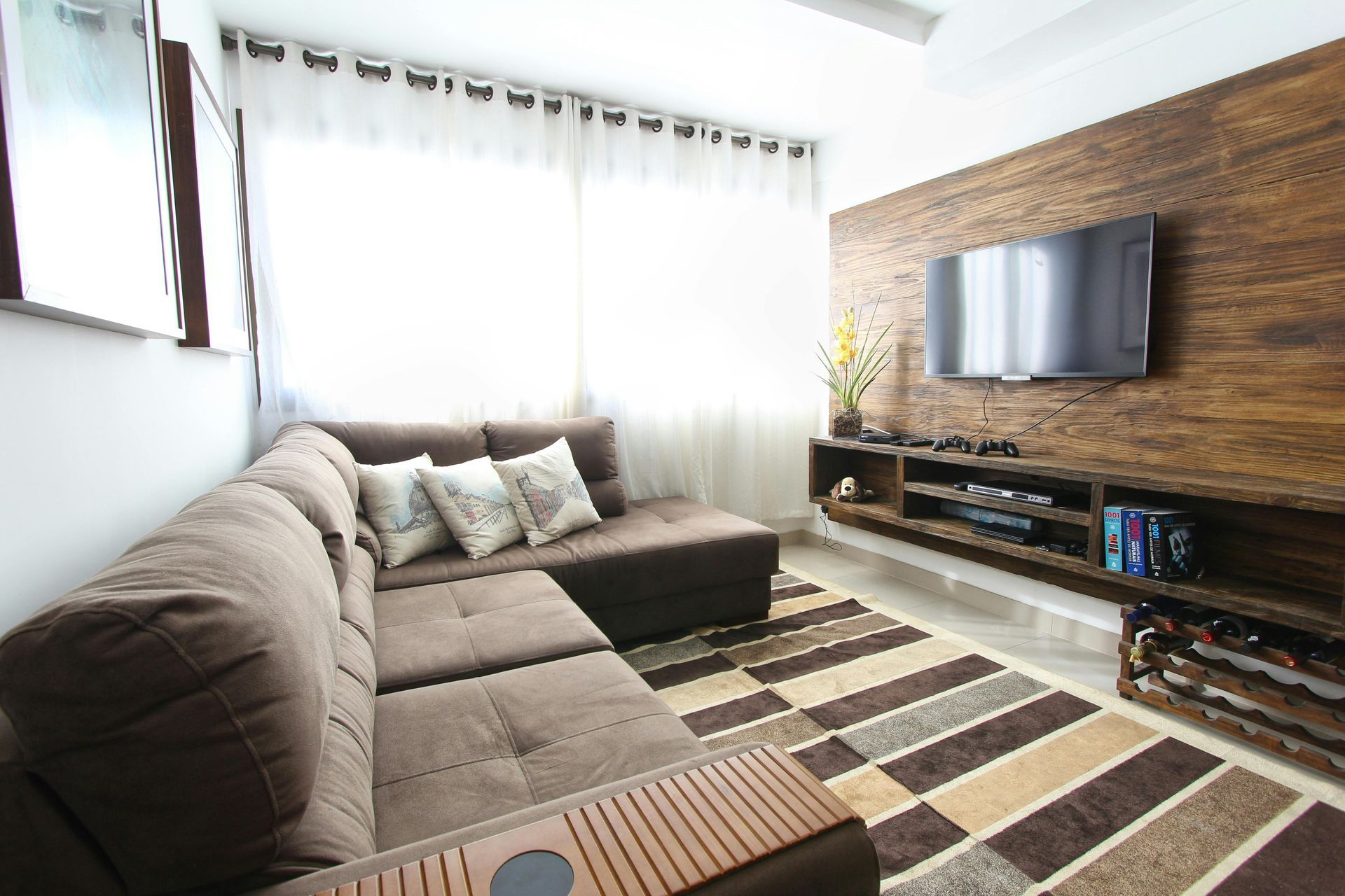 Brown sectional sofa in a living room with a TV mounted on a wooden wall.