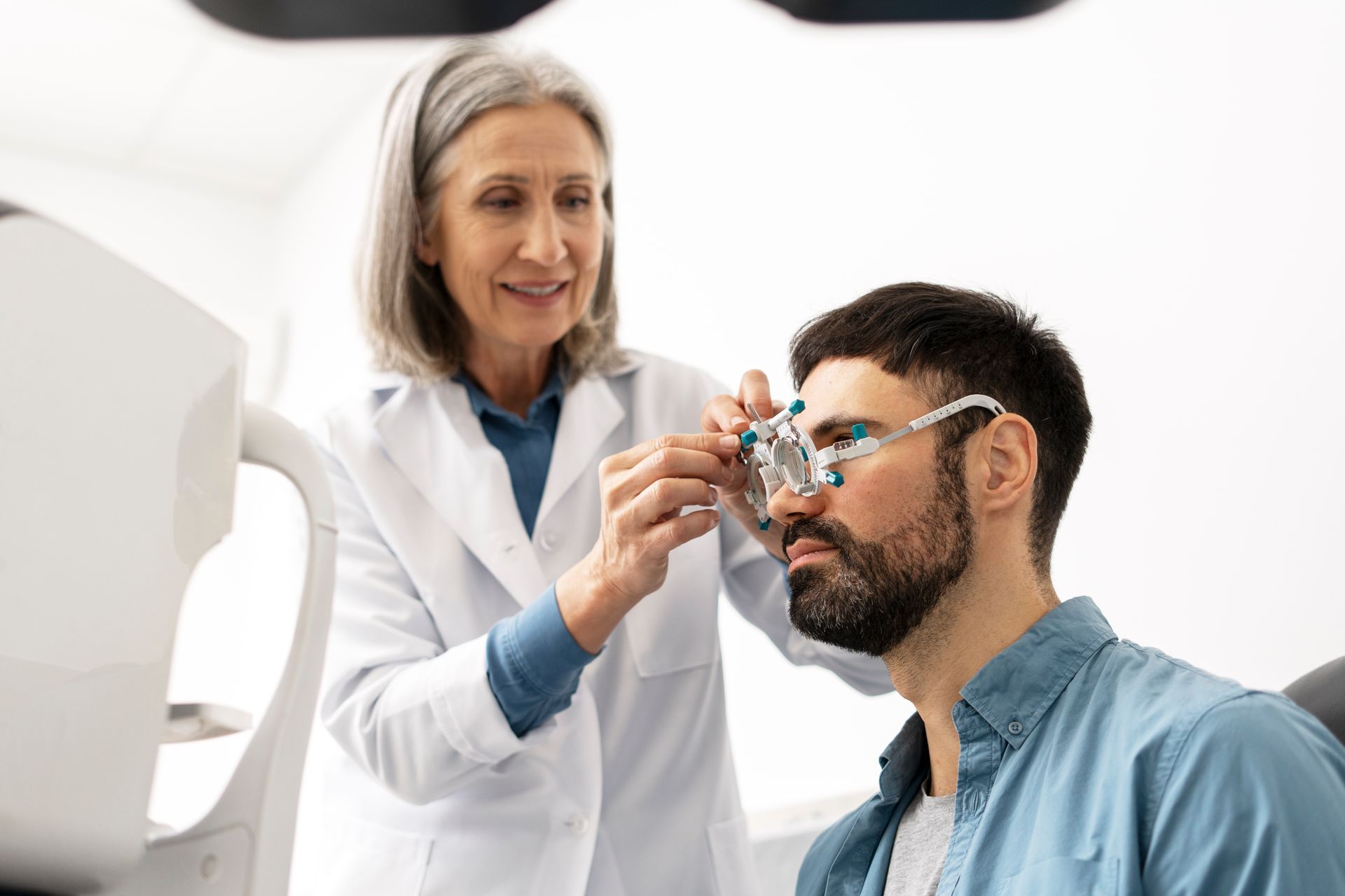 Optometrist adjusting lenses on a patient's face during an eye exam.