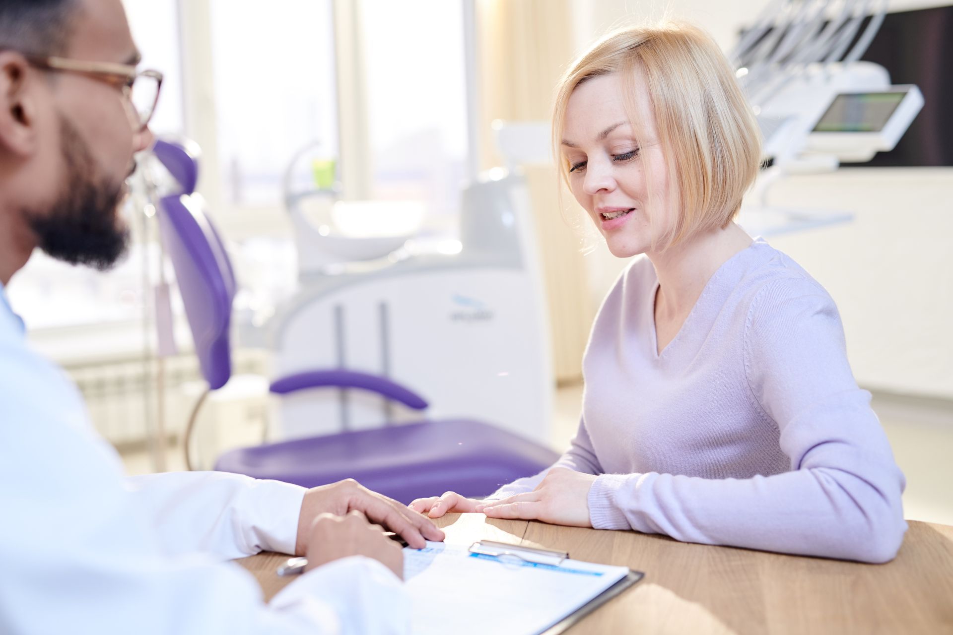 A person in a light purple sweater consults with a doctor in a medical office.