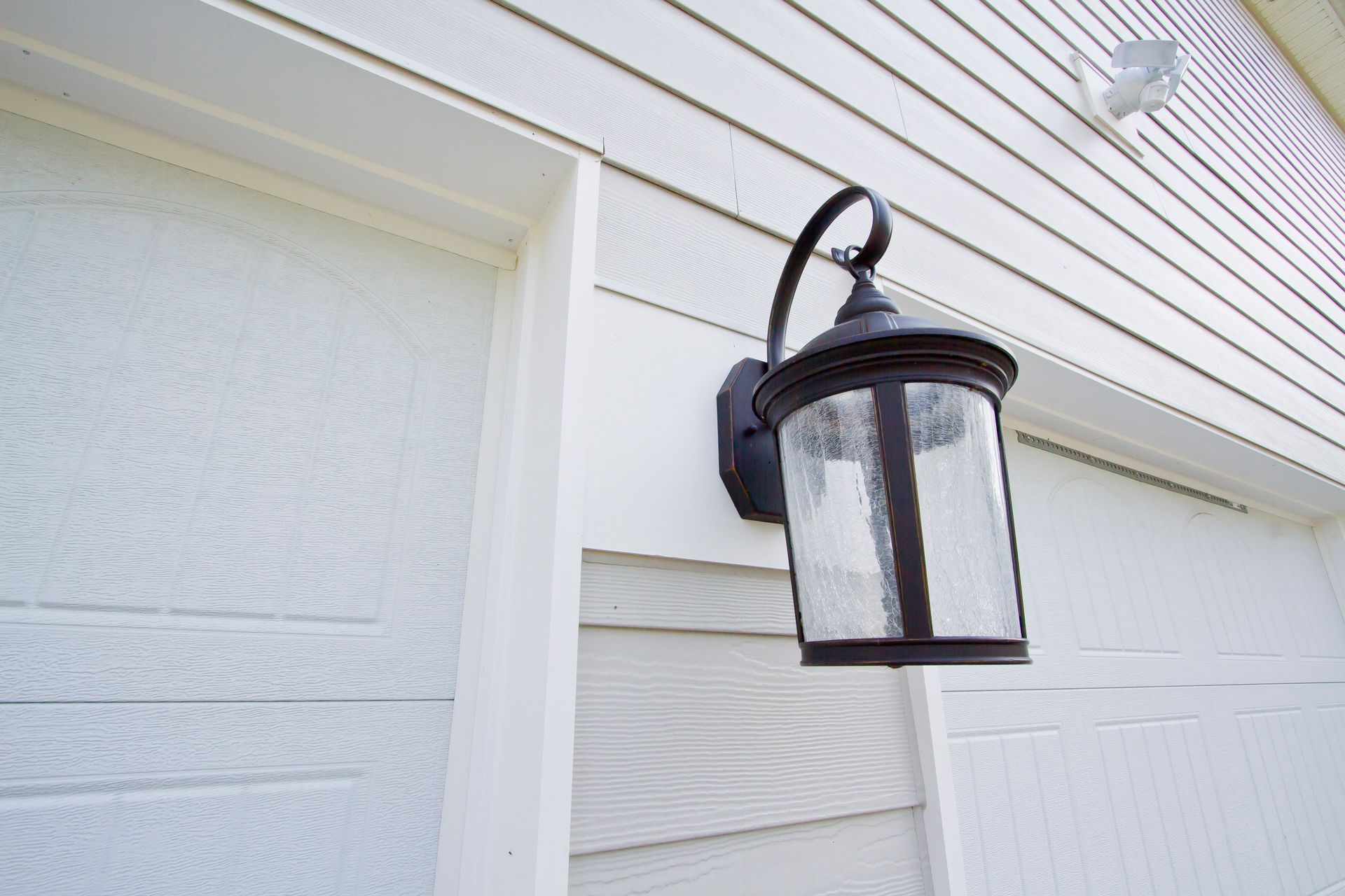 Black outdoor lamp on white siding.