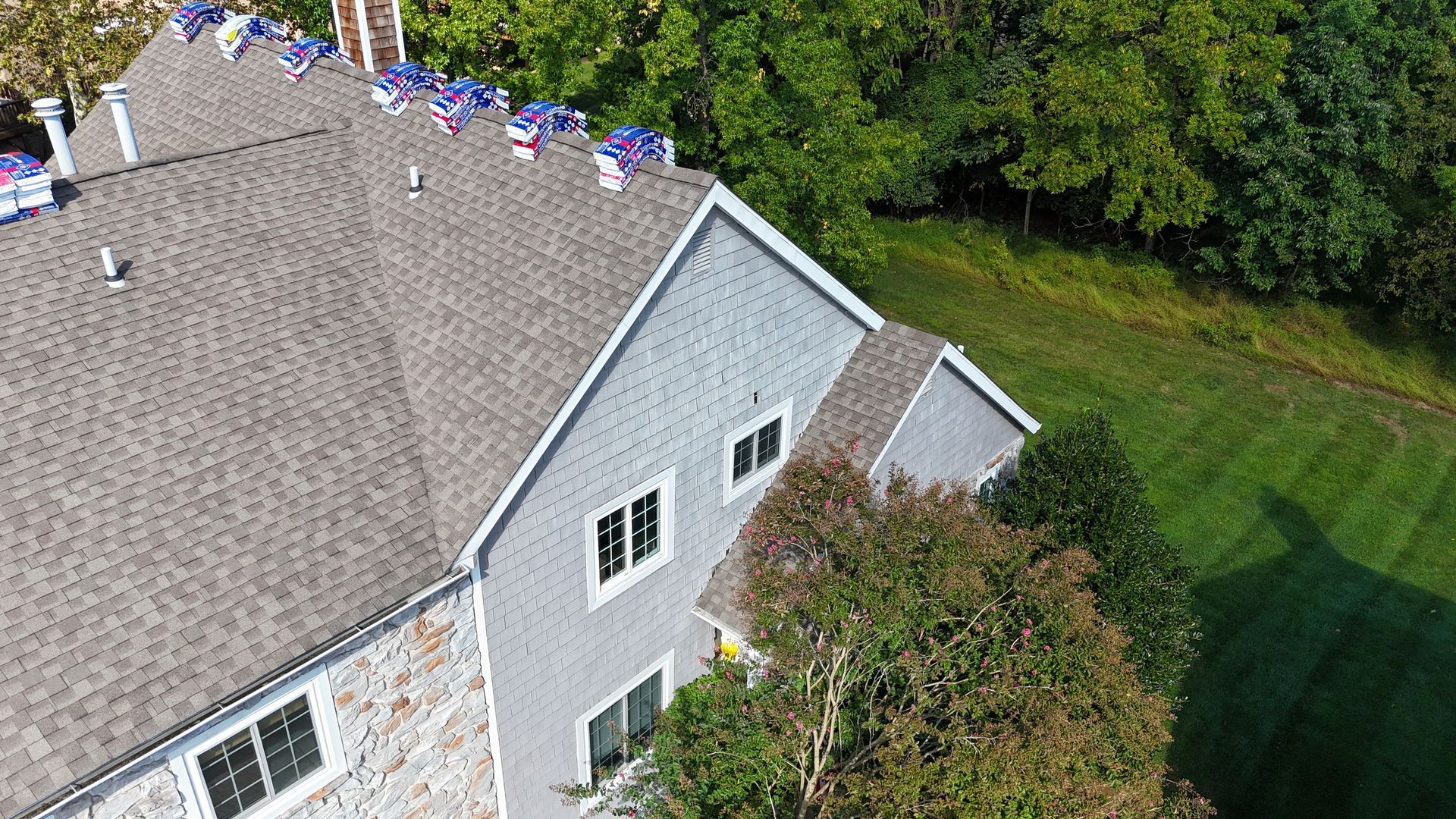 Dark gray shingled roof with a triangular dormer and chimney, viewed from above.