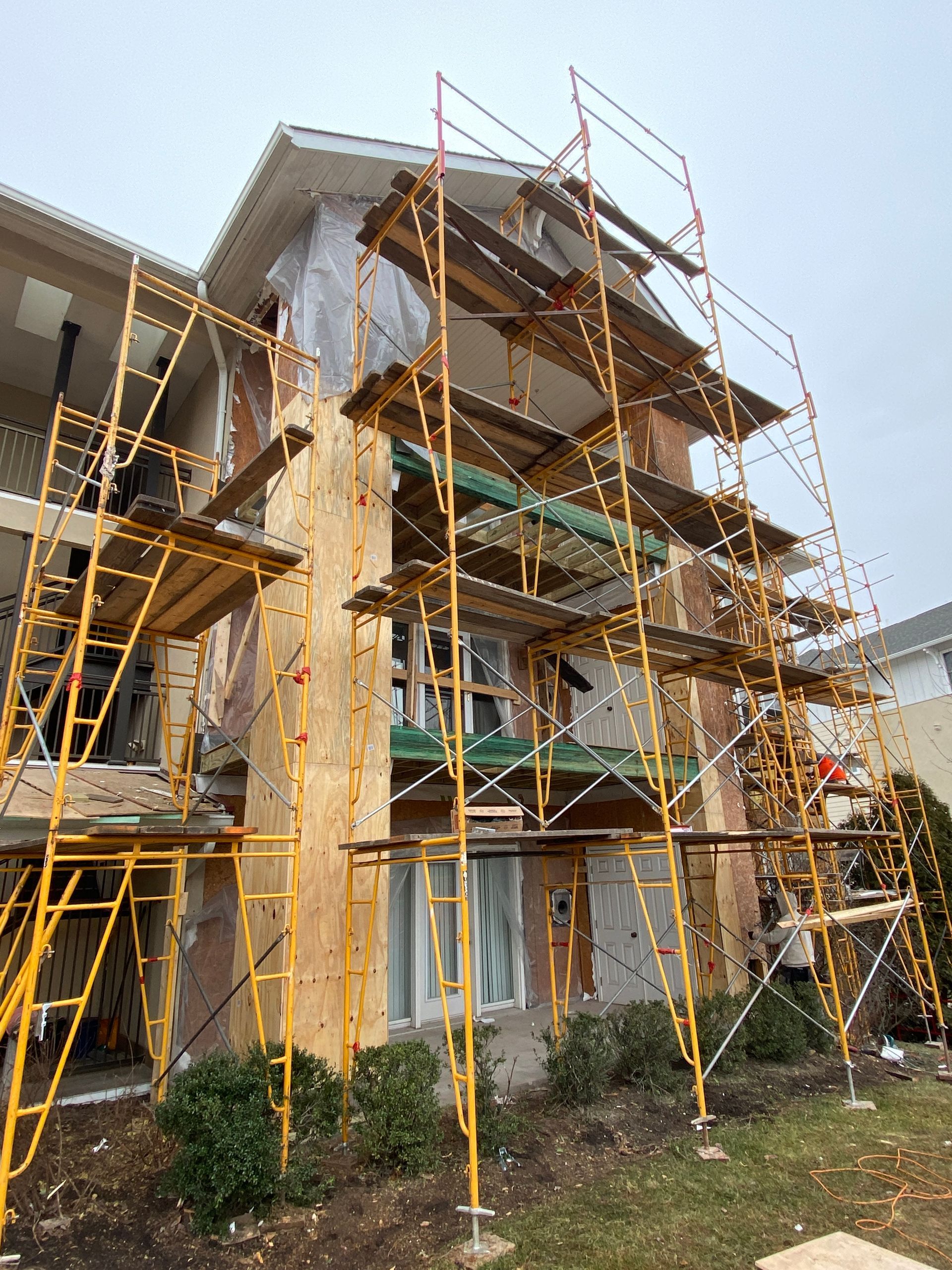 Scaffolding surrounds a multi-story building under construction. The exterior is partly covered in sheathing.