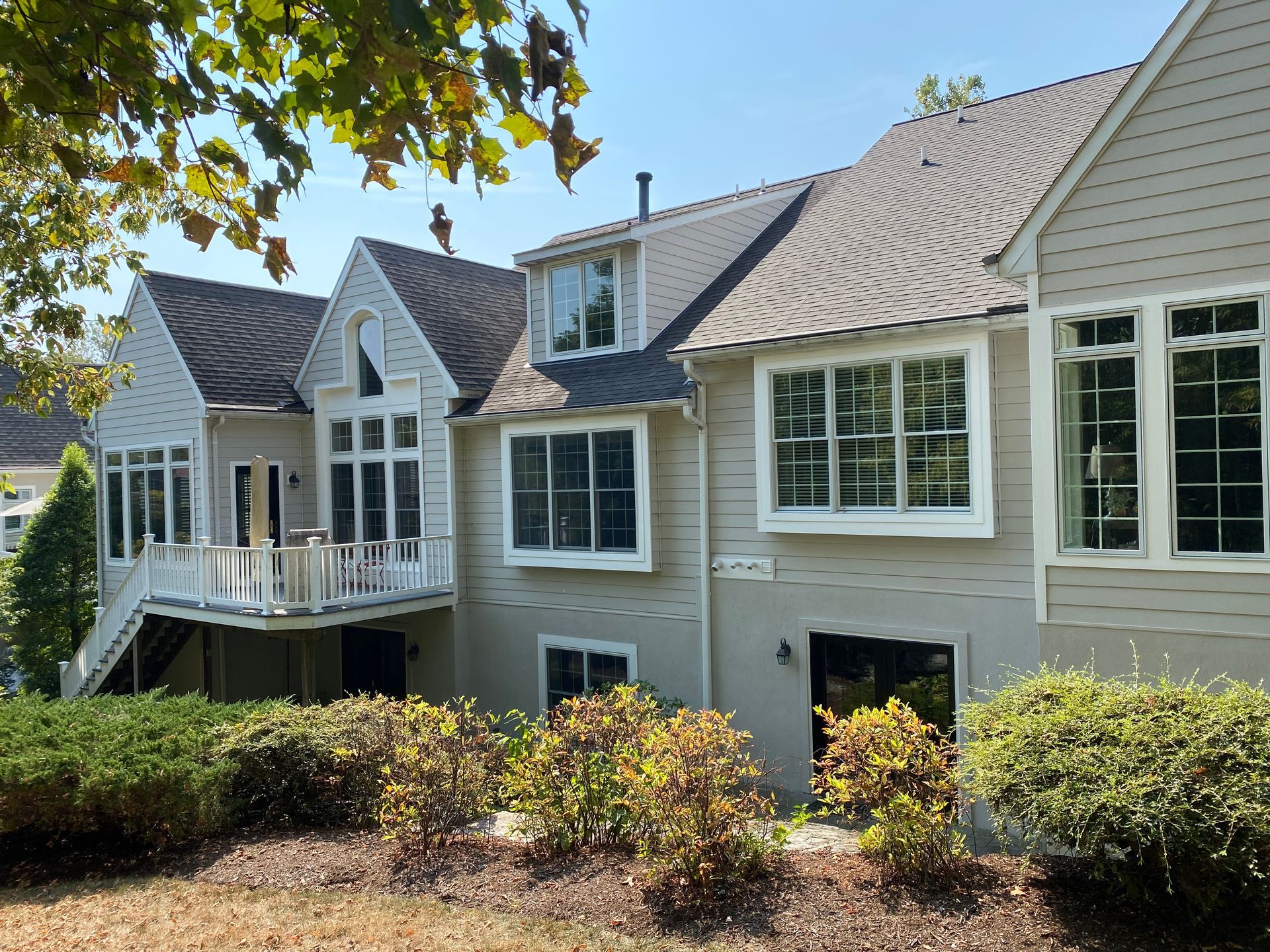 Beige house with a multi-level structure, many windows, and a balcony, under a sunny sky.