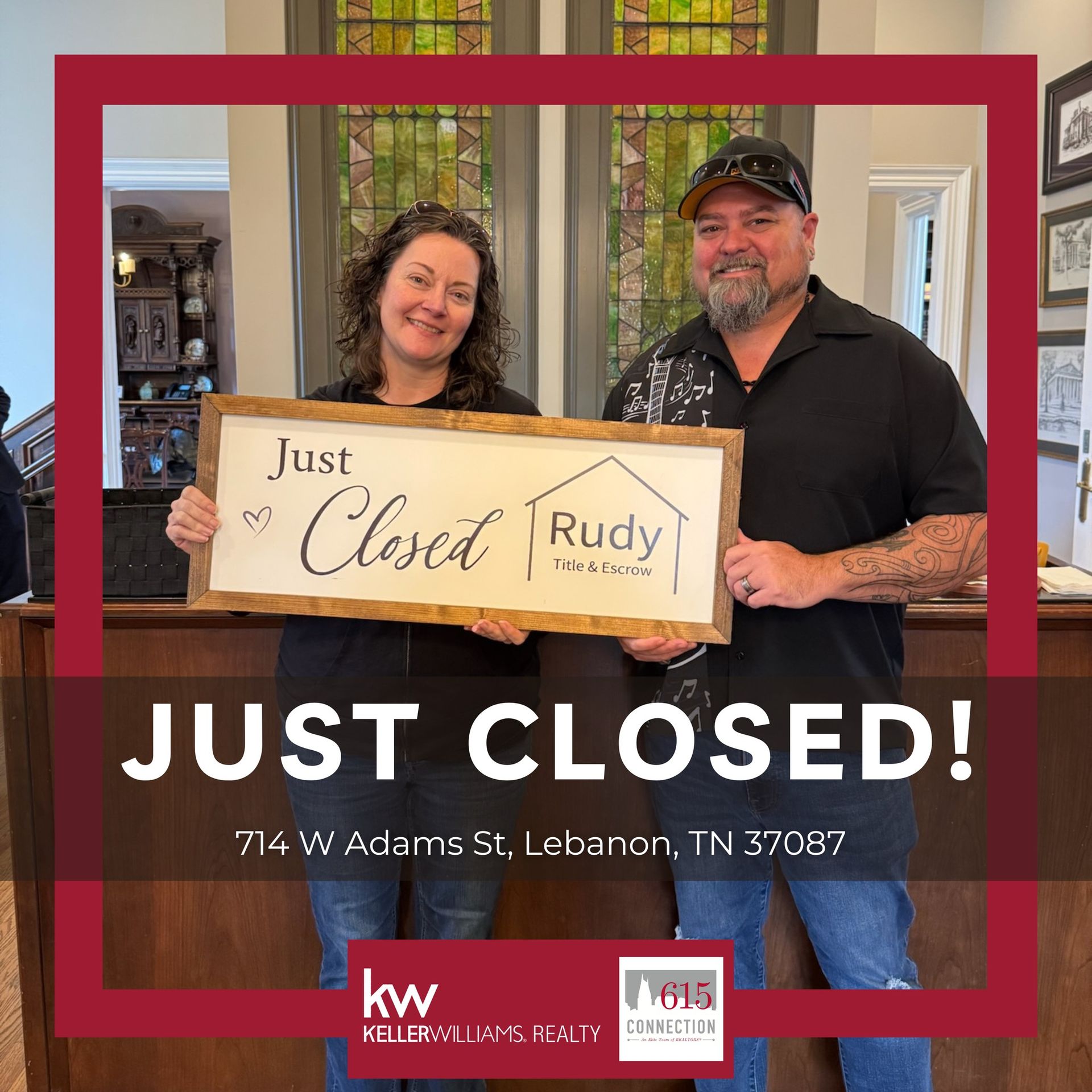 Two people holding a “Just Closed” real estate sign in front of a house
