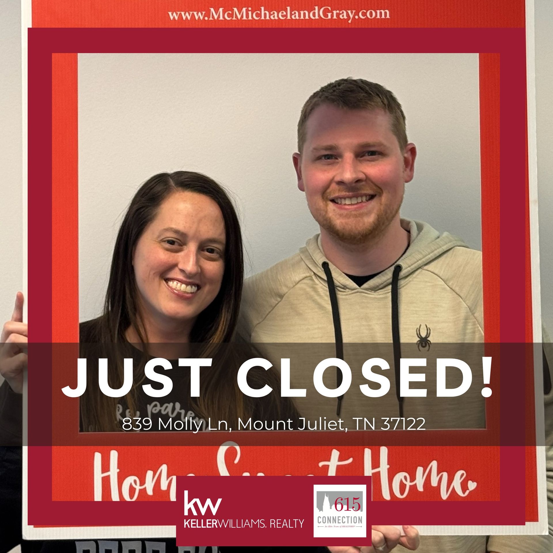 Two smiling people posing in front of a red "Just Closed!" real estate sign