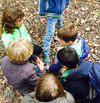 Kinderen in een groepje bij elkaar, overleg bij het onderzoek buiten in de natuur.