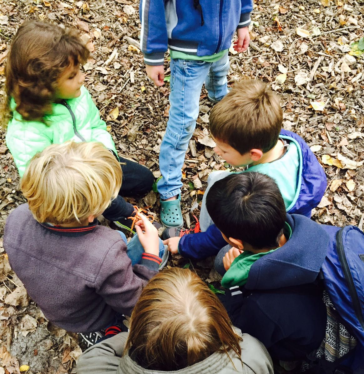Kinderen in een groepje bij elkaar, overleg bij het onderzoek buiten in de natuur.