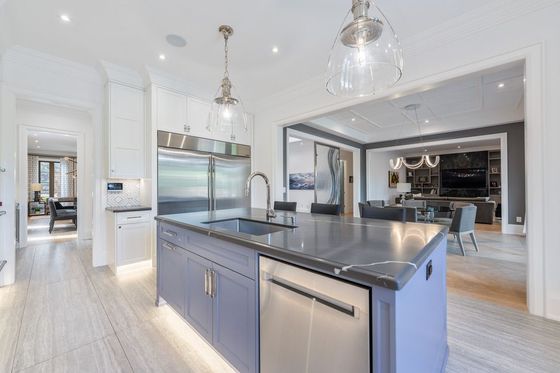 Bright modern kitchen with white cabinetry, gray island, stainless appliances, and hanging glass pendant lights