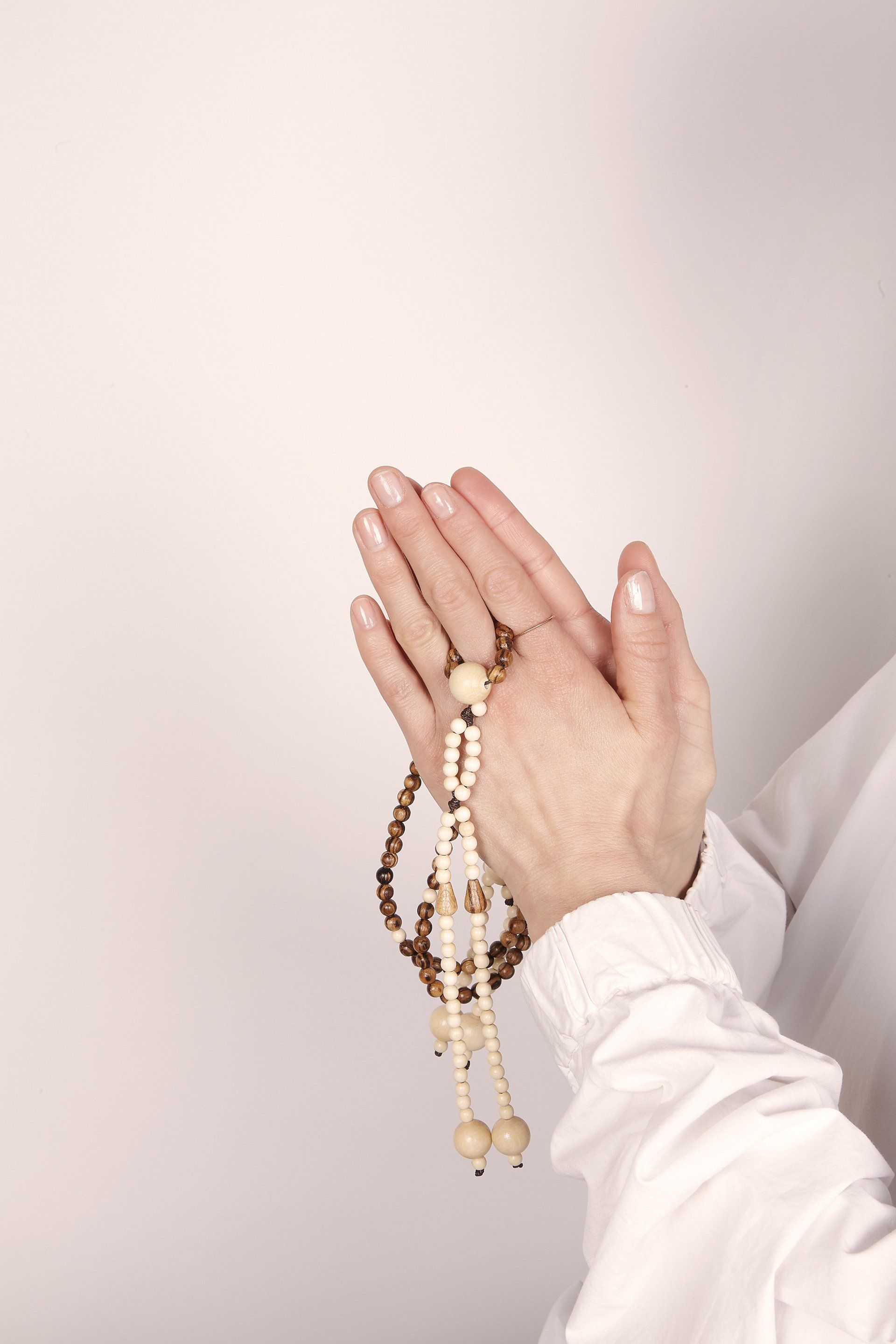 Una persona prega con un rosario in mano.