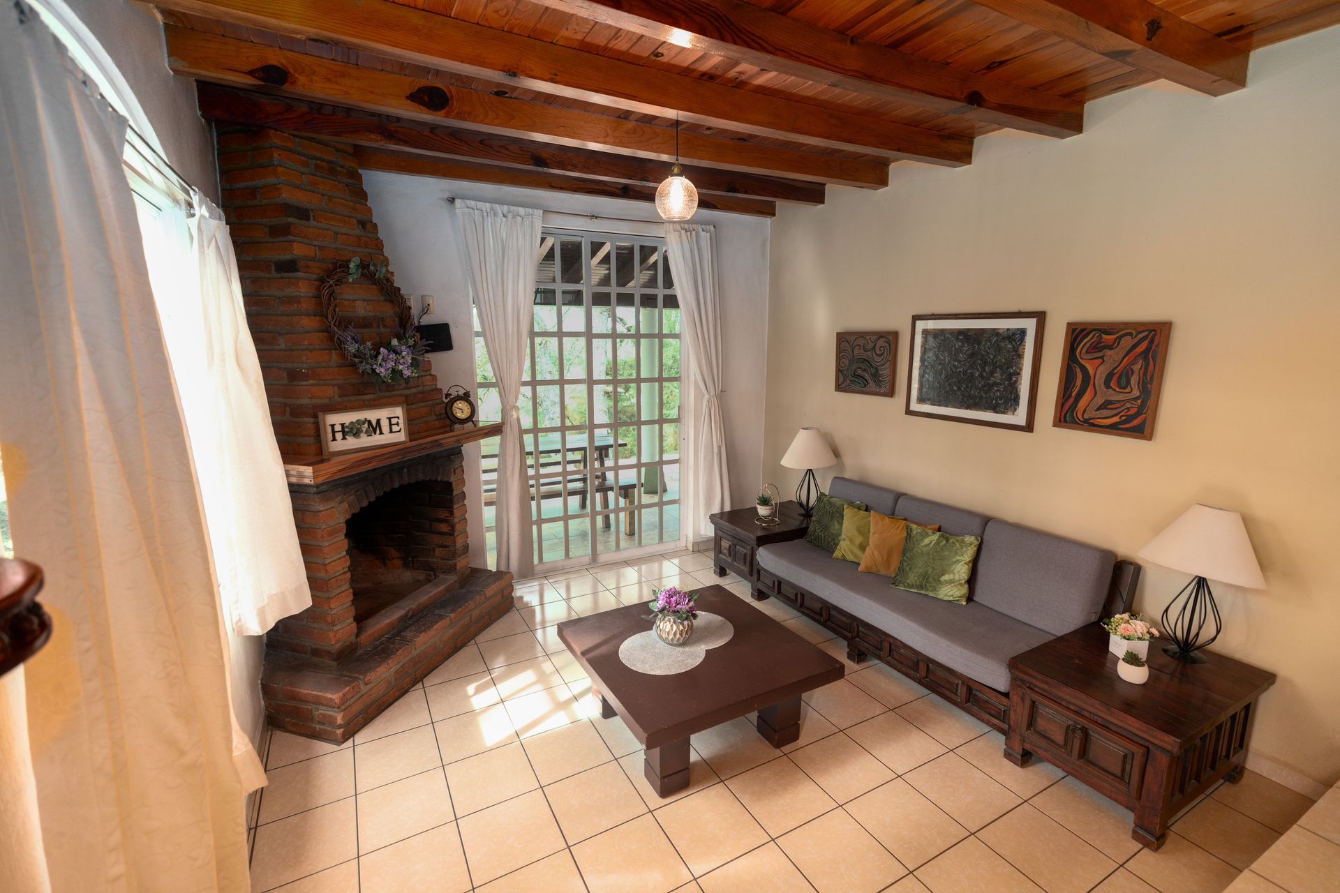 Acogedora sala de estar con chimenea de ladrillo, techo de madera, sofá, mesa de centro