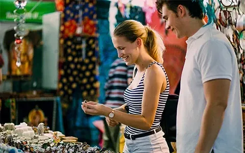 A man and a woman are looking at jewelry at a market.