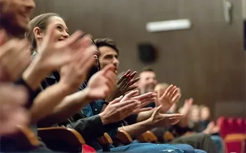 A group of people are clapping their hands in an auditorium.