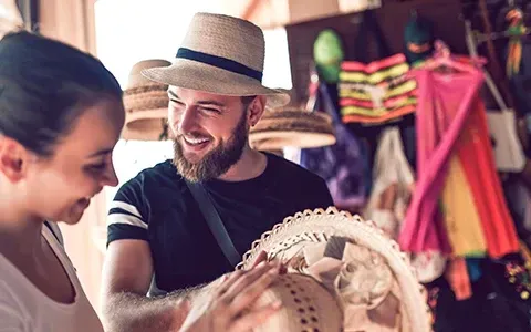 A man and a woman are looking at a hat in a store.