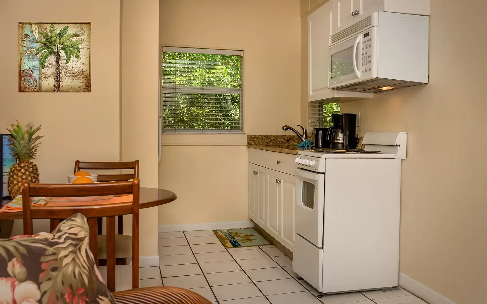 A kitchen with a stove , microwave , refrigerator , table and chairs.