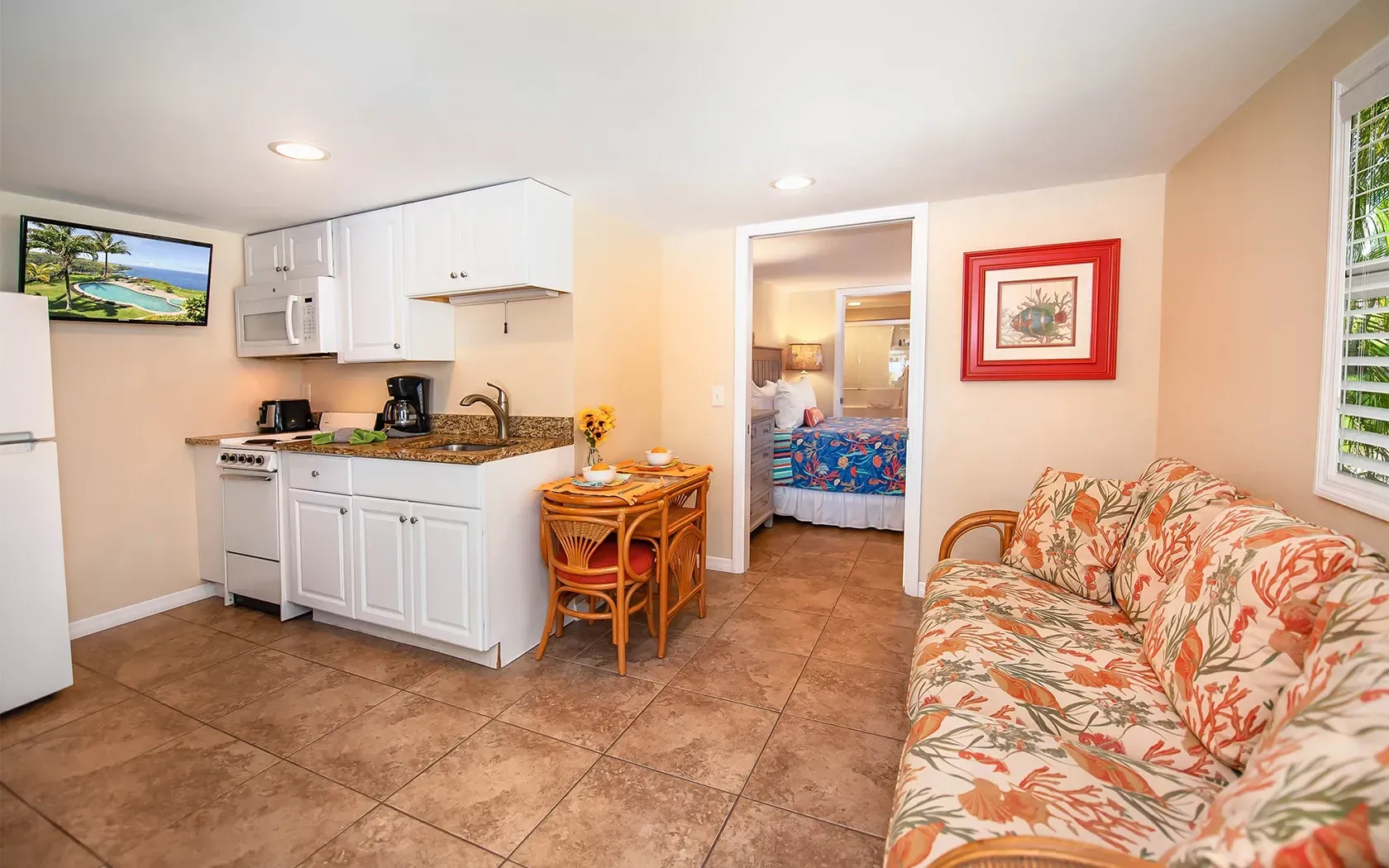 A living room with a couch and a kitchen with a refrigerator.